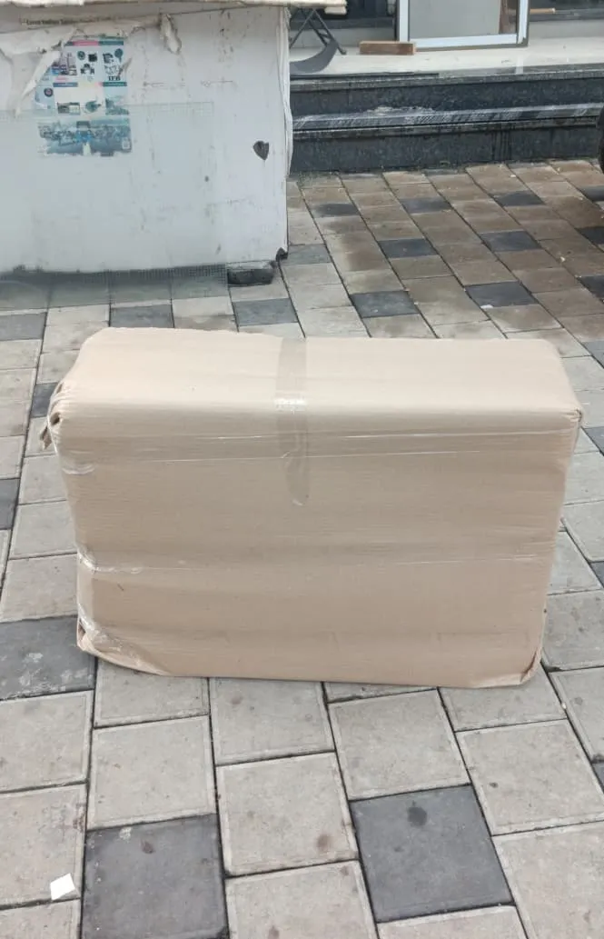 Double-bed mattress boxed in corrugated sheets and taped before loading during a Surat house shifting job