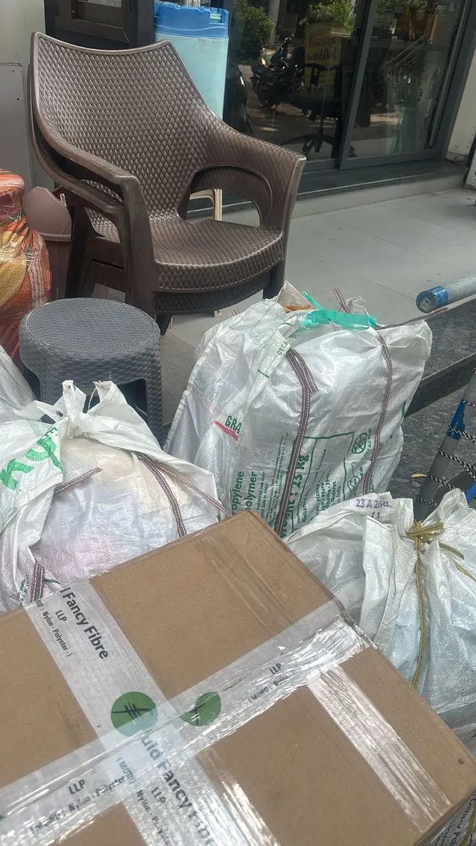 Plastic chairs, stool and woven bags of household goods packed and staged for pickup in Surat