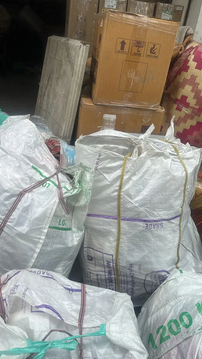 Woven bags of clothes and sealed cartons packed and labelled before loading into the moving truck in Surat