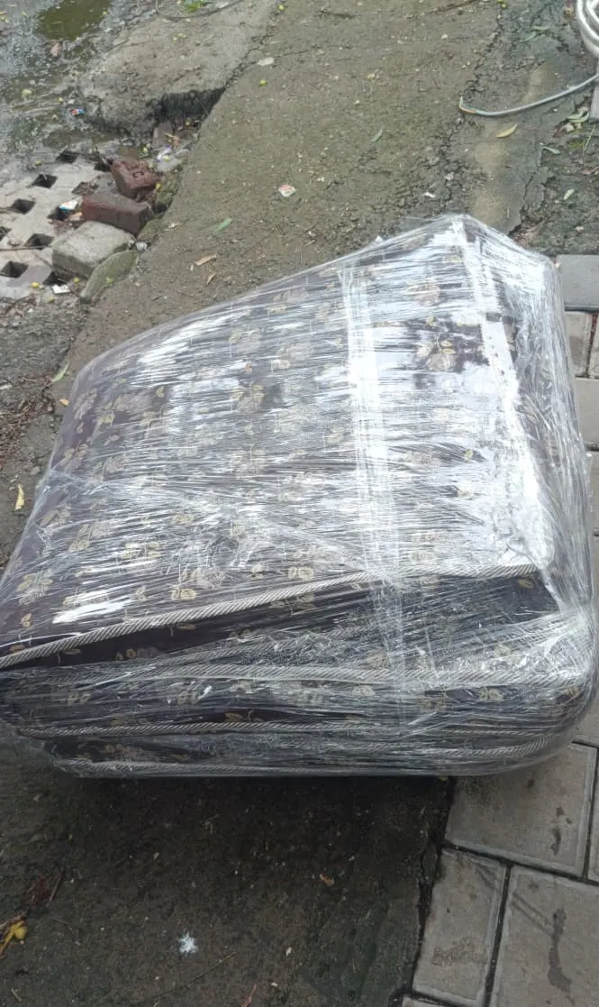 Printed fabric sofa fully wrapped in stretch film to protect upholstery during shifting in Surat