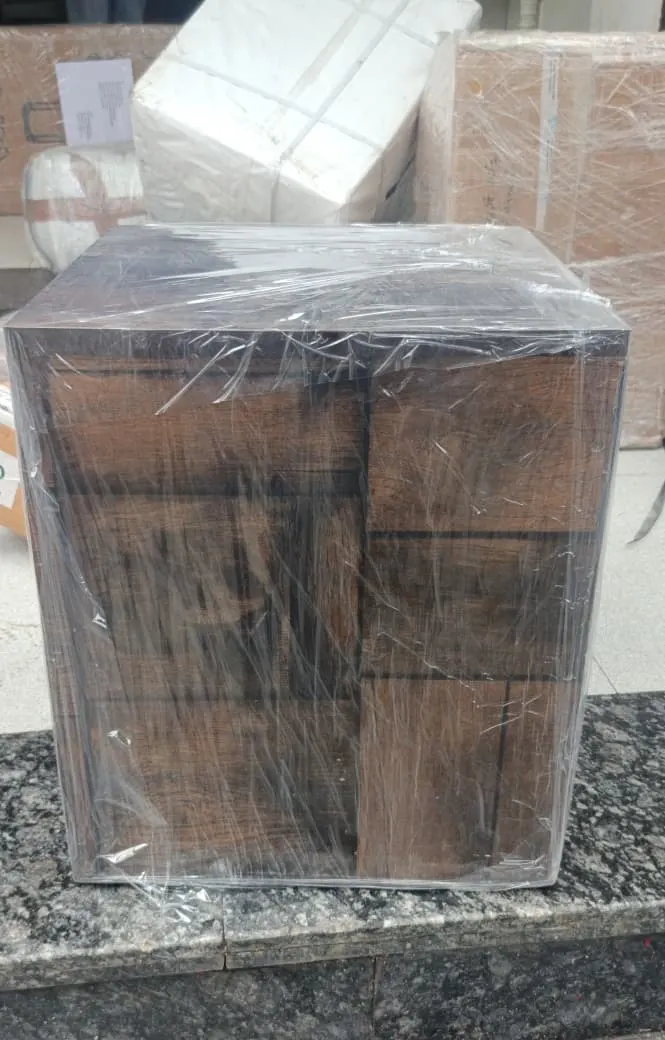 Wooden cabinet shrink-wrapped in stretch film and ready for loading at a Surat home relocation